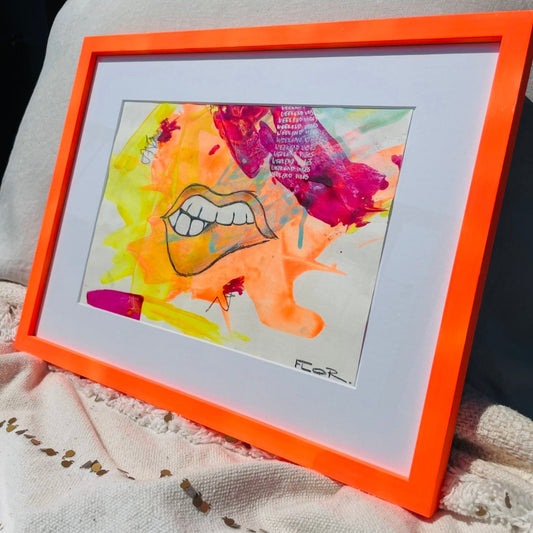 Ein knall orangenes pinks gelbes Bild auf Papier, dass eine Lippe zeigt und auf einem Polster angelehnt steht im Wohnzimmer von FLOR.